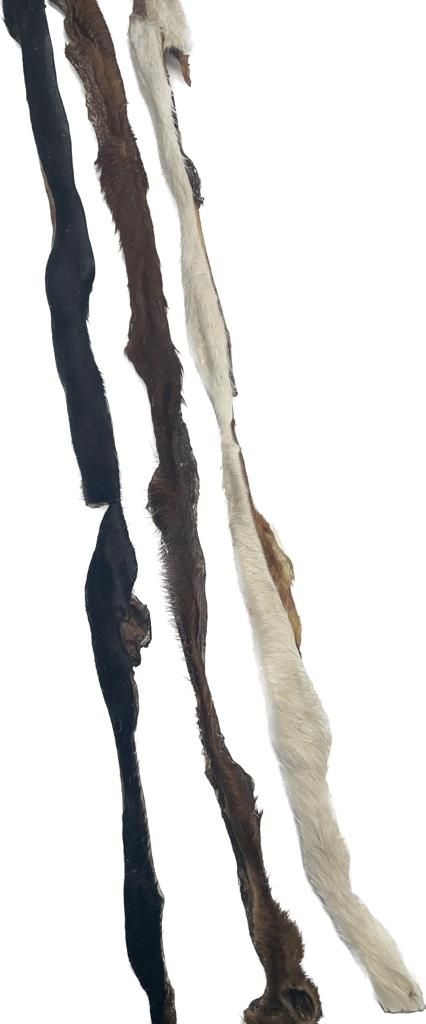 Mehrere lange Rinderkopfhautstangen mit Fell in verschiedenen Farben, darunter Schwarz, Braun und Weiß, mit naturbelassener, zotteliger Struktur.