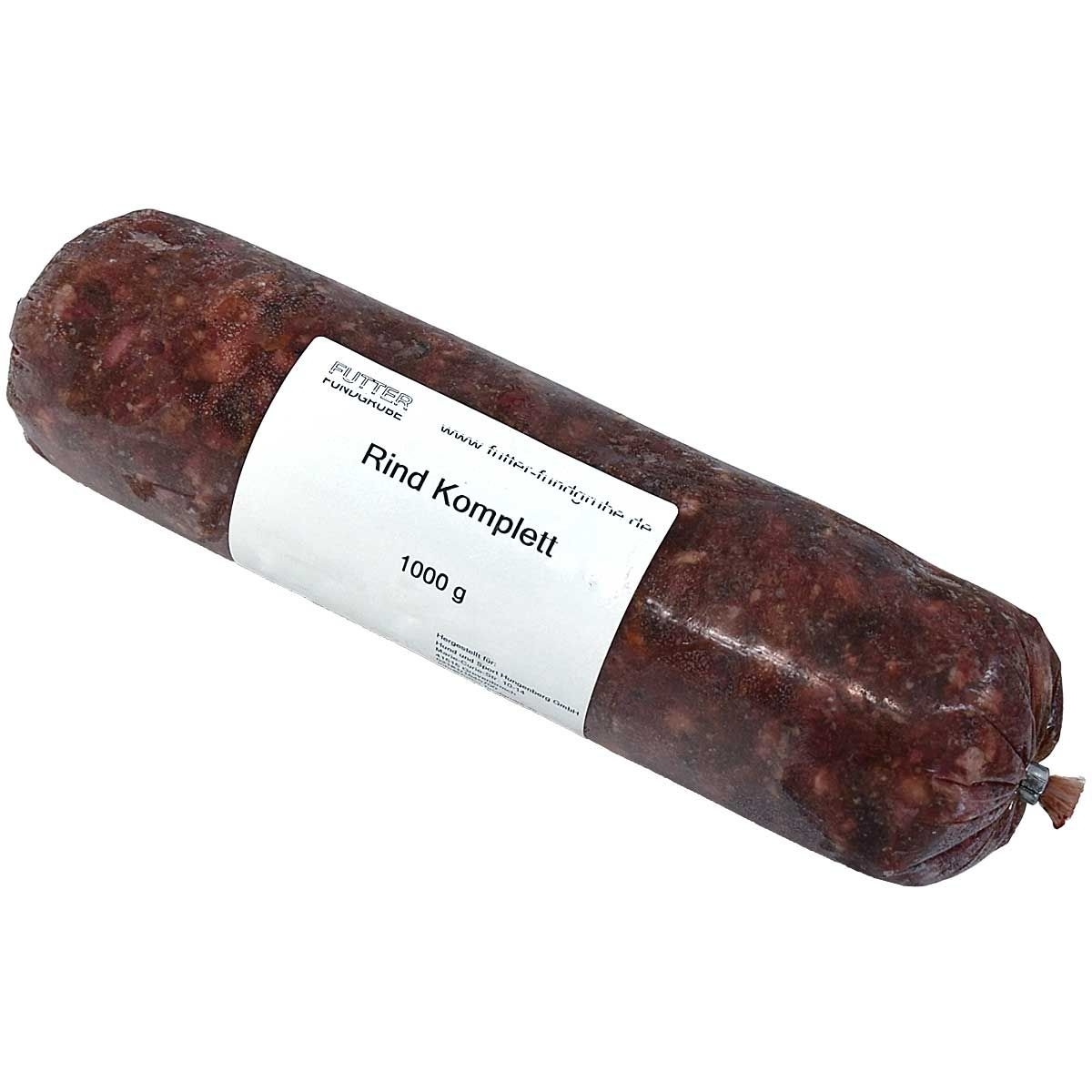Eine Frostfleischrolle mit weißem Etikett und der Aufschrift „Rind Komplett“. Verpackt in einem nicht essbaren Kunstdarm. Die Füllung ist grob gewolft und dunkelrot mit hellen Einschlüssen.