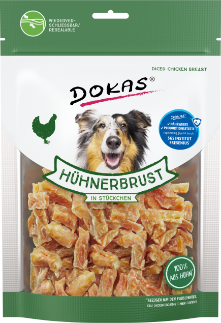 Grün-weiße Verpackung mit Würfeln aus Hühnerbrust, sichtbar durch transparenten Bereich; lachender Hund vorne abgebildet, Beutel mit Zip-Verschluss.