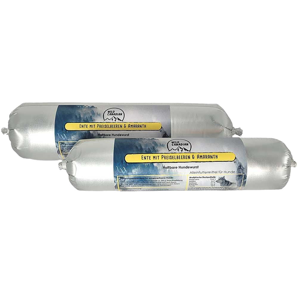Zwei haltbare Hundewürste in silberner Kunststoffhülle. Das Etikett zeigt die Aufschrift „Ente mit Preiselbeeren & Amaranth“ auf gelbem Hintergrund mit Bergmotiv.