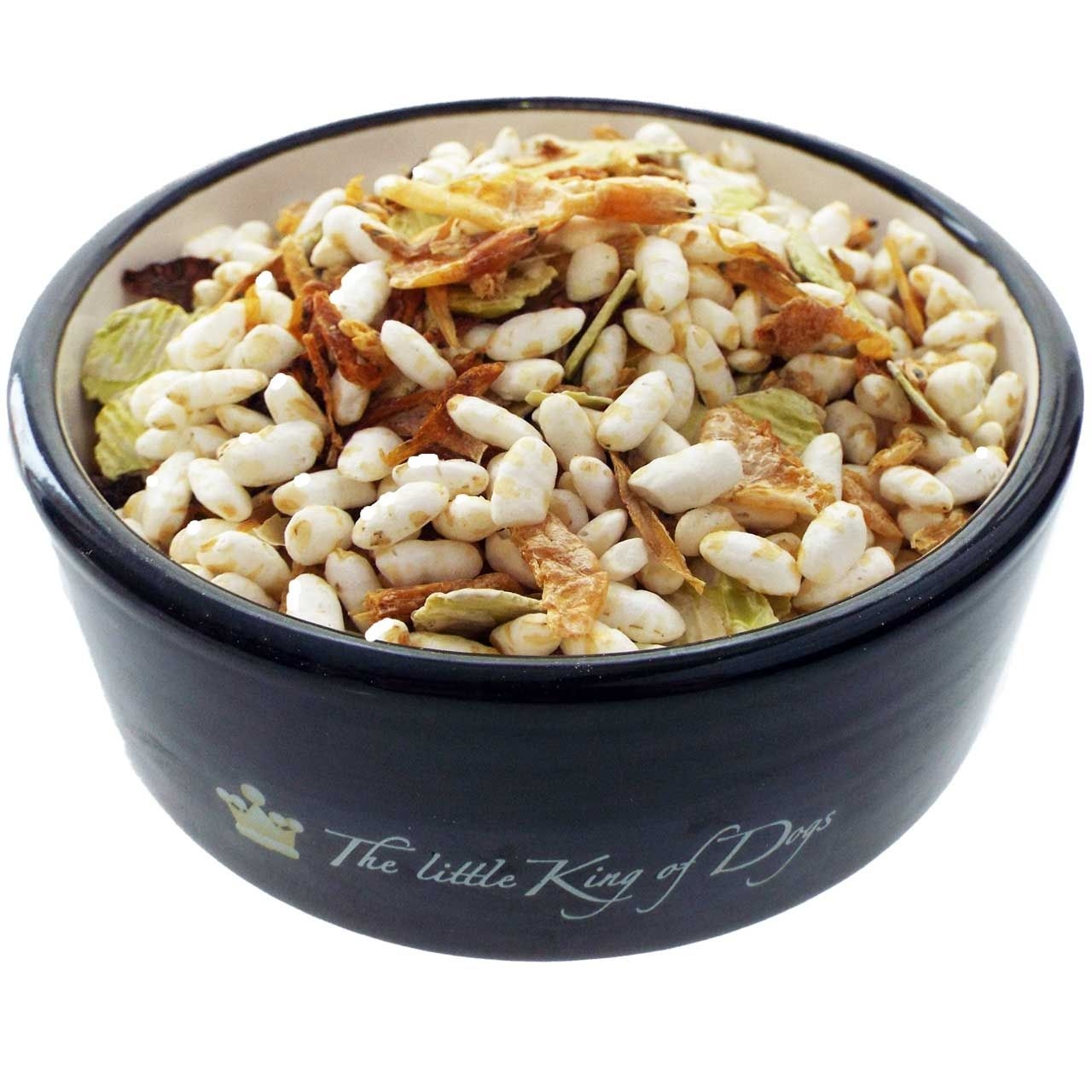 Barfmischung Fisch-Paella 500 g Eine Futtermischung mit weißen Puffreisstücken, getrockneten Gemüseflocken in Beige, Grün und Braun, in einer schwarzen Schale mit heller Innenfläche serviert.