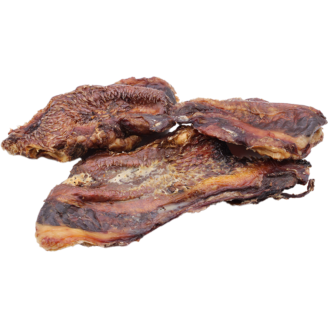 Mehrere flache, unregelmäßig geformte Stücke geräucherten Fleisches mit dunkler, braun-rötlicher Oberfläche und sichtbaren Fettanteilen, leicht glänzend und trocken wirkend.