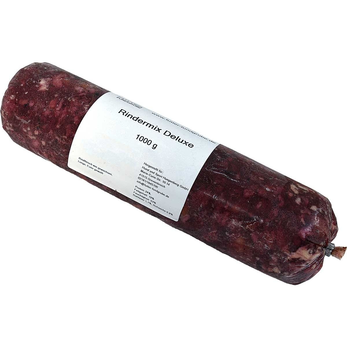 Eine Frostfleischrolle mit weißem Etikett und der Aufschrift „Rindermix Deluxe“. Verpackt in einem nicht essbaren Kunstdarm. Der Inhalt ist grob gewolft und rotbraun mit hellen Stückchen.