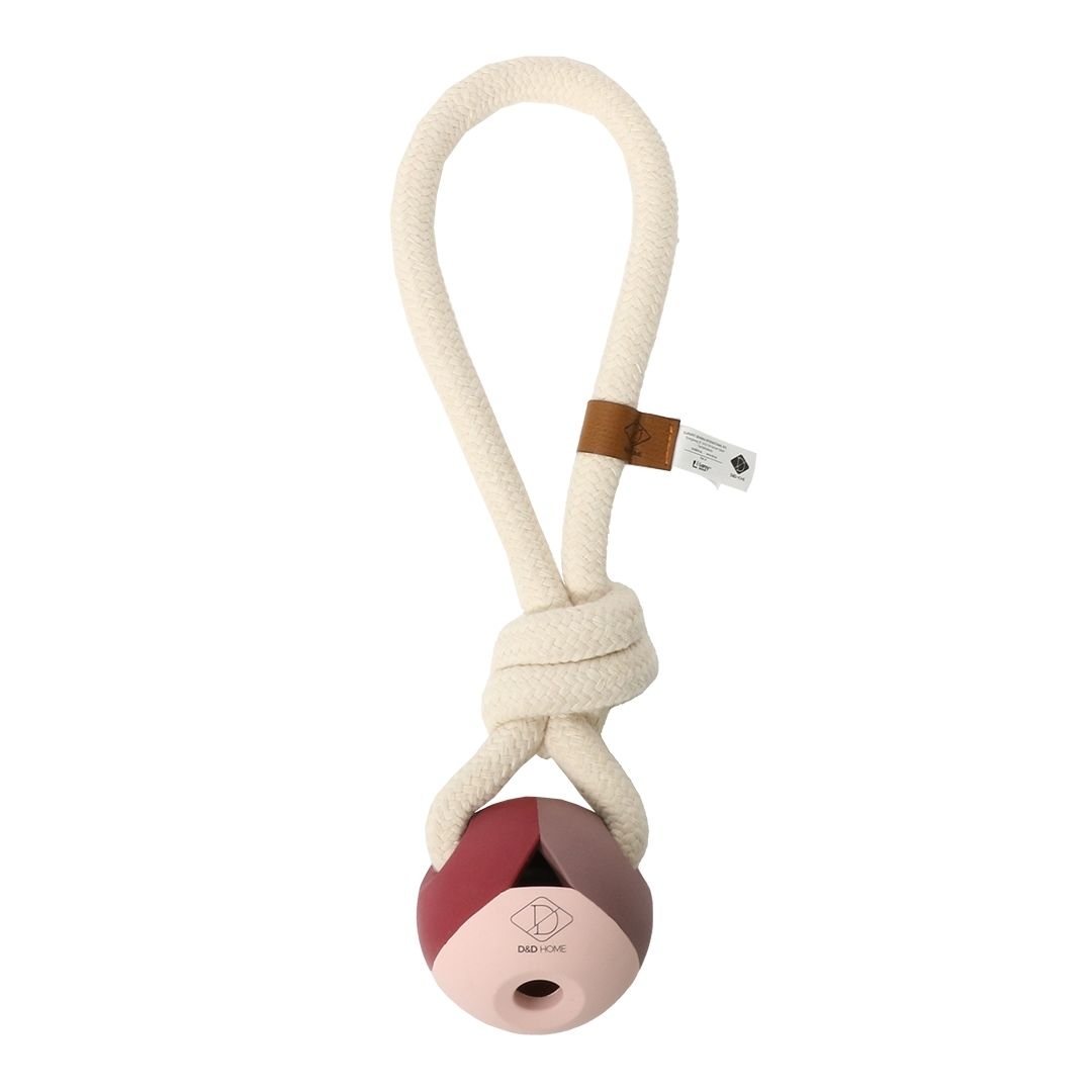 Segmentiertes Hundespielzeug in Rosa-, Rot- und Brauntönen mit dicker, beiger Seilschlaufe und kleinem Lederetikett.