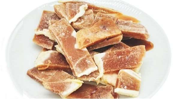 Ein weißer Teller mit mehreren rohen Stücken Entenmuskelfleisch. Die Stücke sind flach, unregelmäßig geformt und zeigen eine rötlich-braune Farbe mit teils sichtbaren weißen Fettanteilen. Sie wirken gefroren und leicht frostig.