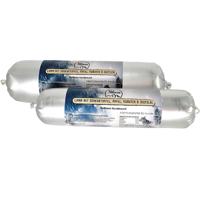 Zwei haltbare Hundewürste in silberner Kunststoffhülle. Das Etikett trägt die Aufschrift „Lamm mit Süßkartoffel, Apfel, Kräuter & Distelöl“ auf dunkelblauem Hintergrund mit Bergmotiv.