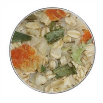 Eine helle Flockenmischung mit grünen, orangefarbenen und weißen Gemüseanteilen in unregelmäßiger Form, gleichmäßig verteilt in einer kreisrunden Ansicht.