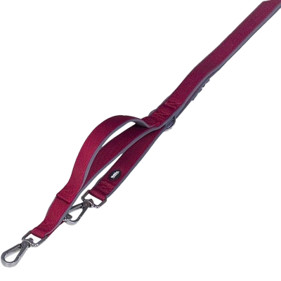 Eine doppelte Hundeleine aus rotem Gurtband mit zwei Karabinerhaken und verstellbarer Schlaufe. Das Material wirkt robust, mit feiner Webstruktur und dunklen Metallbeschlägen.