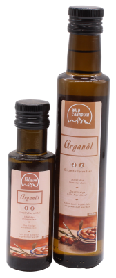 Zwei braune Glasflaschen mit schwarzem Schraubverschluss und beigen Etiketten der Marke „Wild Canadian“. Beide tragen die Aufschrift „Arganöl“ und zeigen Arganfrüchte