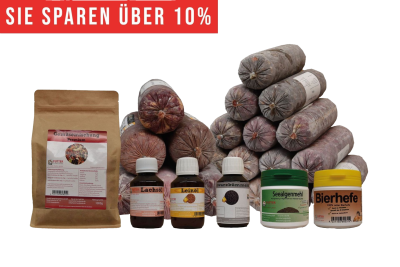 Ein vielseitiges BARF-Paket mit pyramidenförmig gestapelten Frostfleischrollen in grauem Kunstdarm. Davor stehen Flachbeutel mit rotem Inhalt, ein brauner Standbeutel, vier kleine Fläschchen und zwei Dosen.