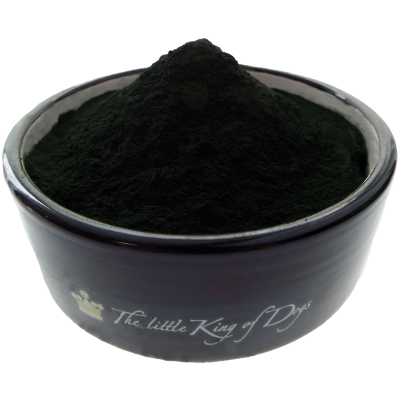 Ein dunkelgrünes Pulver mit feiner Struktur, aufgeschüttet zu einem Haufen in einem dunkelblauen Keramiknapf mit weißer Innenwand.