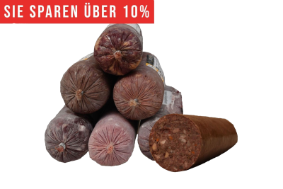 Eine Pyramide aus runden Frostfleischrollen in graubraunem Kunstdarm. Rechts daneben eine angeschnittene Wurst mit dunklem Fleisch und sichtbaren hellen und orangen Stücken.