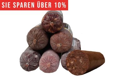 Eine Pyramide aus runden Frostfleischrollen in graubraunem Kunstdarm. Rechts daneben eine angeschnittene Wurst mit dunklem Fleisch und sichtbaren hellen und orangen Stücken.