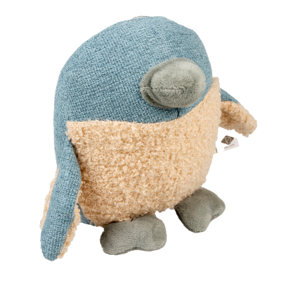 Plüschspielzeug in Vogeloptik mit blauem Stoff an Kopf, Flügeln und Rücken; beige, lockige Struktur am Bauch; grauer Schnabel und Füße, kleines Etikett am Flügel.