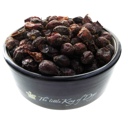 Getrocknete, dunkelrote Hagebutten mit runzliger Oberfläche in einem schwarzen Napf mit hellem Innenrand.