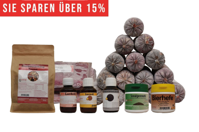 Ein vielseitiges BARF-Paket mit pyramidenförmig gestapelten Frostfleischrollen in grauem Kunstdarm. Davor stehen Flachbeutel mit rotem Inhalt, ein brauner Standbeutel, vier kleine Fläschchen und zwei Dosen.