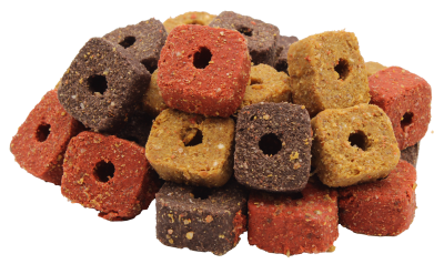 Würfelförmige Hunde-Leckerlis mit Loch in der Mitte in gemischten Farben: rot, gelb und dunkelbraun. Die Snacks wirken körnig und weich