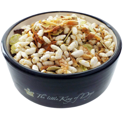 Eine Futtermischung mit weißen Puffreisstücken, getrockneten Gemüseflocken in Beige, Grün und Braun, in einer schwarzen Schale mit heller Innenfläche serviert.