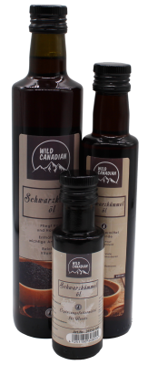 Drei braune Glasflaschen in unterschiedlichen Größen mit schwarzem Schraubverschluss und beigem Etikett mit der Aufschrift „Wild Canadian Schwarzkümmelöl“. Ergänzungsfuttermittel für Hunde.