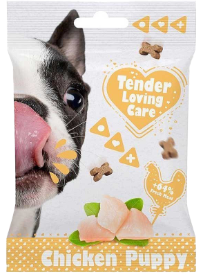 Verpackung mit Hundebild, Herzsymbol und kleinen Knochenformen. Unten Stücke Hühnerfleisch mit grünen Blättern. Text im Herz: ‚Tender Loving Care‘.