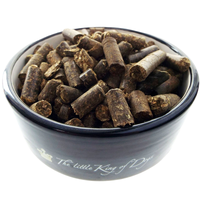 Dunkelbraune Pellets mit grober, faseriger Oberfläche in einer schwarz glänzenden Schale mit weißem Innenrand, locker geschichtet.