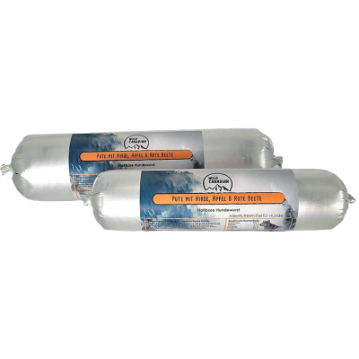 Zwei haltbare Hundewürste in silberner Kunststoffhülle. Das Etikett zeigt die Aufschrift „Pute mit Hirse, Apfel & Rote Beete“ vor einem blauen Bergmotiv.