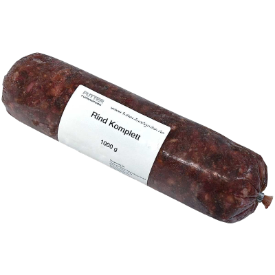 Eine Frostfleischrolle mit weißem Etikett und der Aufschrift „Rind Komplett“. Verpackt in einem nicht essbaren Kunstdarm. Die Füllung ist grob gewolft und dunkelrot mit hellen Einschlüssen.