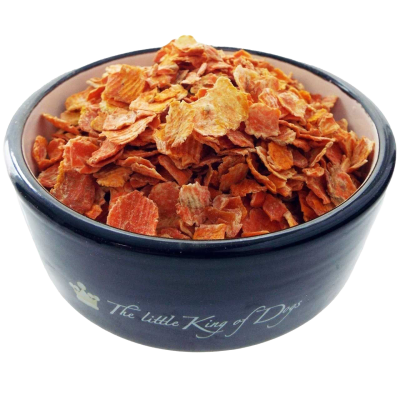 Ein schwarzer Napf mit der Aufschrift „The little King of Dogs“, gefüllt mit orangefarbenen, flachen Möhrenflocken. Die Flocken sind dünn, unregelmäßig geformt und leicht gewellt.