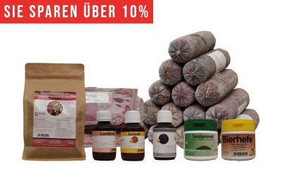 Ein vielseitiges BARF-Paket mit pyramidenförmig gestapelten Frostfleischrollen in grauem Kunstdarm. Davor stehen Flachbeutel mit rotem Inhalt, ein brauner Standbeutel, vier kleine Fläschchen und zwei Dosen.