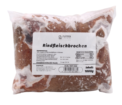 Ein transparenter Kunststoffbeutel mit gefrorenen Rindfleischbrocken in rötlich-brauner Farbe, unregelmäßig geformt und von weißlichen Eiskristallen überzogen, mit aufgeklebtem weißem Etikett auf der Vorderseite.